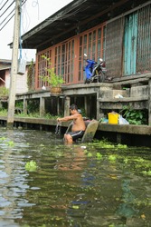 Damnoensaduak floating market, Bangkok, Thailand - June 22, 2014 : People washing cloths near the river in floating market.