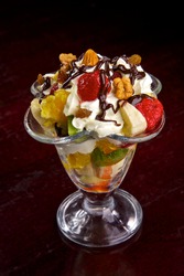 Fresh fruit in cream. A dessert from fruit and cream. Walnuts, a strawberry, a kiwi, pineapple, an apple, a banana, an orange in cream with chocolate