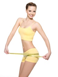 Smiling woman with beautiful body measuring thigh with measurement type after diet, isolated on white.