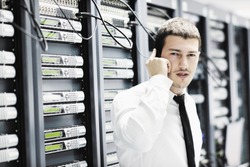 young business man computer science engeneer talking by cellphone at network datacenter server room asking for help and fast solutions and services