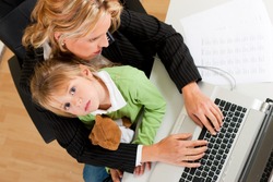 Family Business - telecommuter Businesswoman and mother is working in the internet while her daughter looks to the viewer