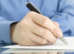 pen in hand writing on the page and reflection