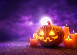 A glowing Pumpkin Jack-O-Lantern against purple sky background on Halloween, mixed media illustration.
