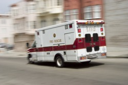 An ambulance blazes by, it's sirens whaling. An intensional camera blur gives a feeling of a rushed tension to the scene.