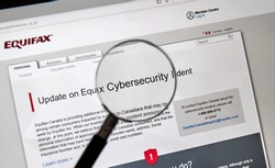 MONTREAL, CANADA - SEPTEMBER, 25 : Equifax Canada home page with information about cybersecurity incident under magnifying glass. Equifax Inc. is a consumer credit reporting agency. Selective focus.