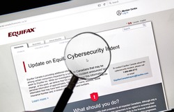 MONTREAL, CANADA - SEPTEMBER, 25 : Equifax Canada home page with information about cybersecurity incident under magnifying glass. Equifax Inc. is a consumer credit reporting agency. Selective focus.