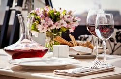 Fine restaurant dinner table place setting: napkin, wineglass, plate, bread and flowers