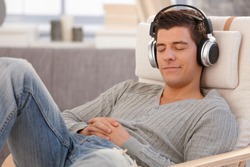 Young man relaxing with headphones, listening to music with eyes closed, smiling.?