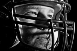 This is a high contrast, black and white image of a young man with an intense look on his face wearing a football helmet. Processed to enhance skin texture.