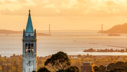 Sunset time Sather Tower at University of California, Berkeley campus, with Golden Gate Bridge in the background.