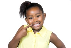 Close up portrait of cute little african girl with ponytail pointing with finger at teeth.Isolated on white background.