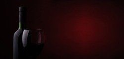 Wine glass and bottle on a dark red background with space for text