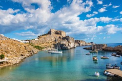 Fishing boats and sail boats in St. Paul´s bay, Lindos acropolis in background (Rhodes, Greece)