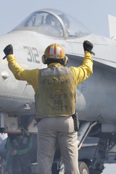 A "Yellow Shirt" Aircraft Director Loads an F/A-18C Hornet onto a Catapult on the Nuclear Aircraft Carrier, USS Enterprise