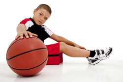 Portrait over white of young boy child basketball player sitting with ball relaxing.