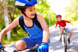 Two little boys riding bikes one after another