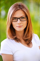 Portrait of young attractive blonde woman wearing eyeglasses and white blouse at summer green park.