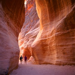 The Siq, the narrow slot-canyon that serves as the entrance passage to the hidden city of Petra, Jordan, seen here with tourists walking.This is an UNESCO World Heritage Site