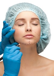 Beautiful young woman with perforation lines on her face before plastic surgery operation. Beautician touching woman face.