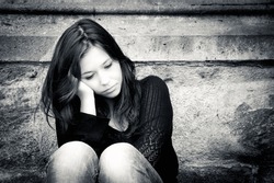 Outdoor portrait of a sad teenage girl looking thoughtful about troubles, toned black and white photo