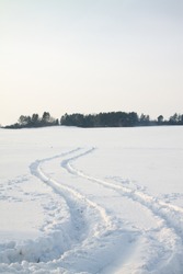 The traces left on snow from the lorry (on a sunset, traces pass through a field, instead of through road)