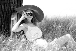 Girl sitting near tree with vintage camera. Photo in old yellow color image style.