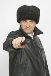 A man in Russian clothing complete with a 9mm automatic handgun pointed at the camera