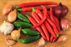 Vegetables against wooden background: onion, garlic, chili peppers and green peppers