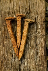 Iconic photo of three rusty spikes lying on a wooden beam. (Symbolic image of Jesus' crucifixion.)