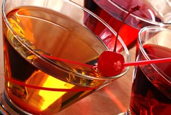 Tilted composition of cocktail drinks with backlighting and abstract reflections. Macro with shallow dof. Selective focus on the cherry.