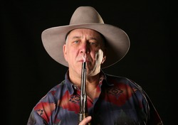 A cowboy blows smoke from the barrel of a freshly fired Colt Navy 44 caliber black powder revolver