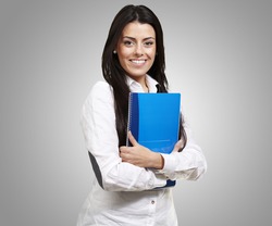 young woman smiling and holding a notebook against a grey background