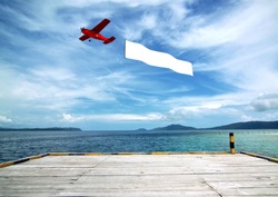 Flying banner pulled by airplane flying over a beautiful tropical beach