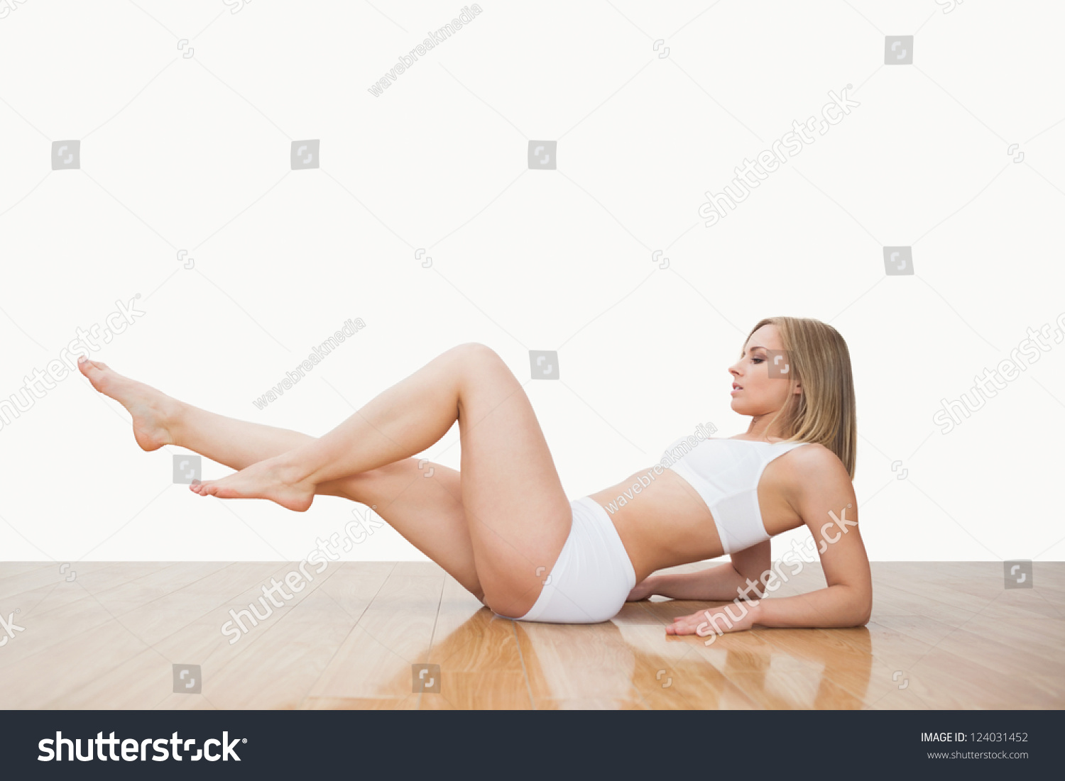 Сидя на полу девушка поднимает ногу фото