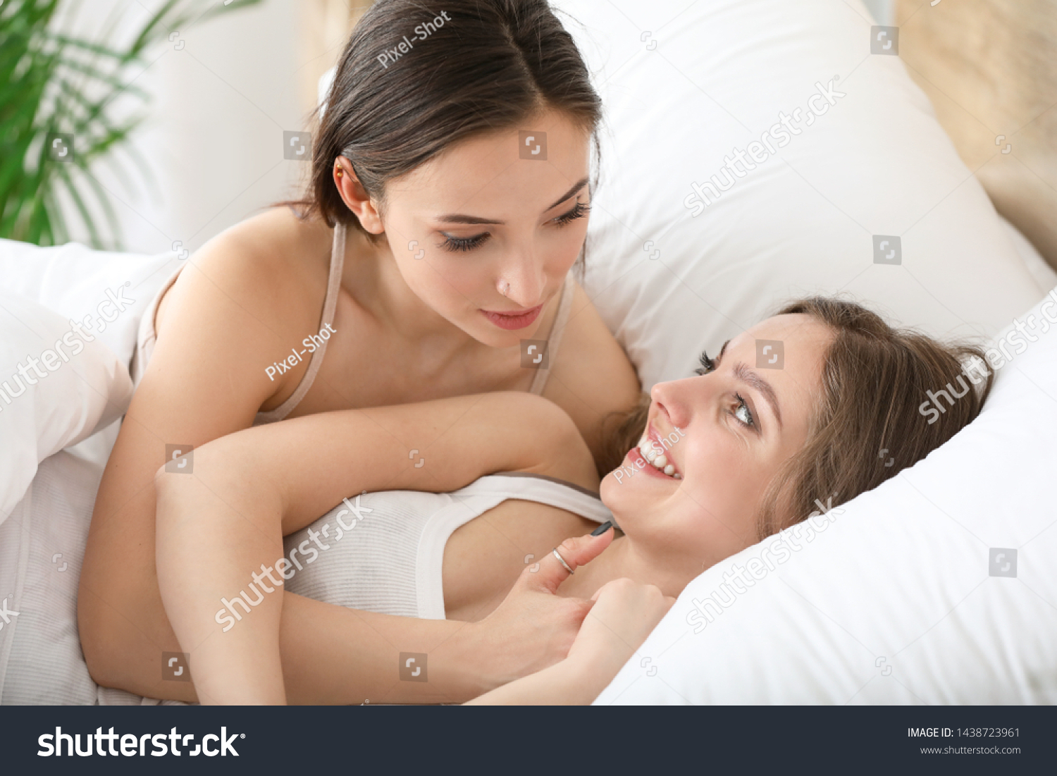 Две молодые лесбиянки лежат на постели и светят большими титьками