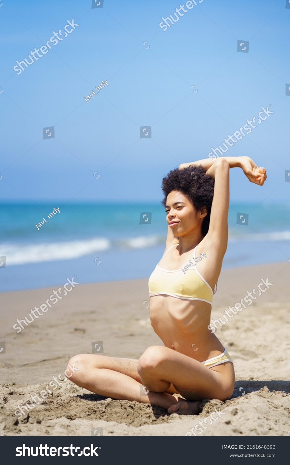 Black Woman Wearing Yellow Bikini Sitting Stock Photo