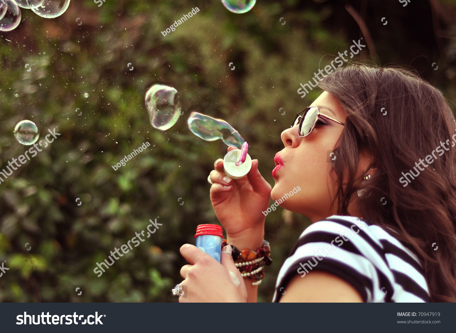 Студентка в очках расслабляется с бутылочкой мыльных пузырей в пилотке