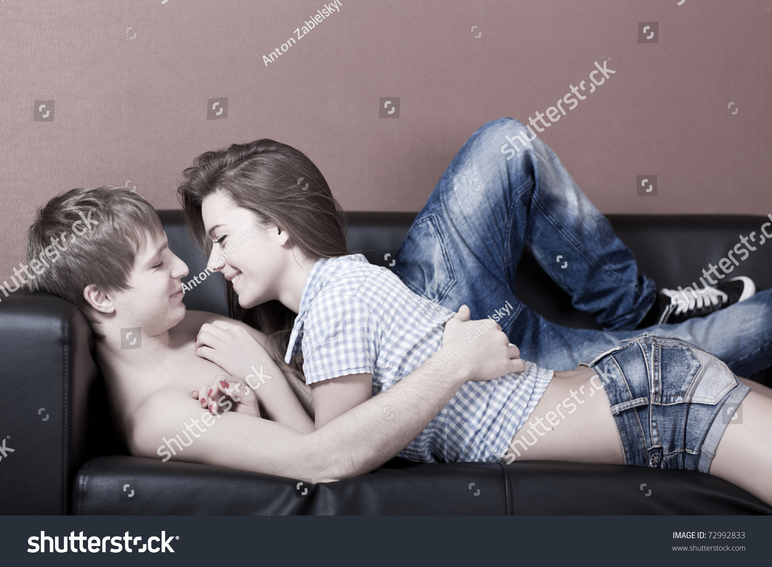 Две голые стриптизерши с длинными ножками эротично целуются на диванчике