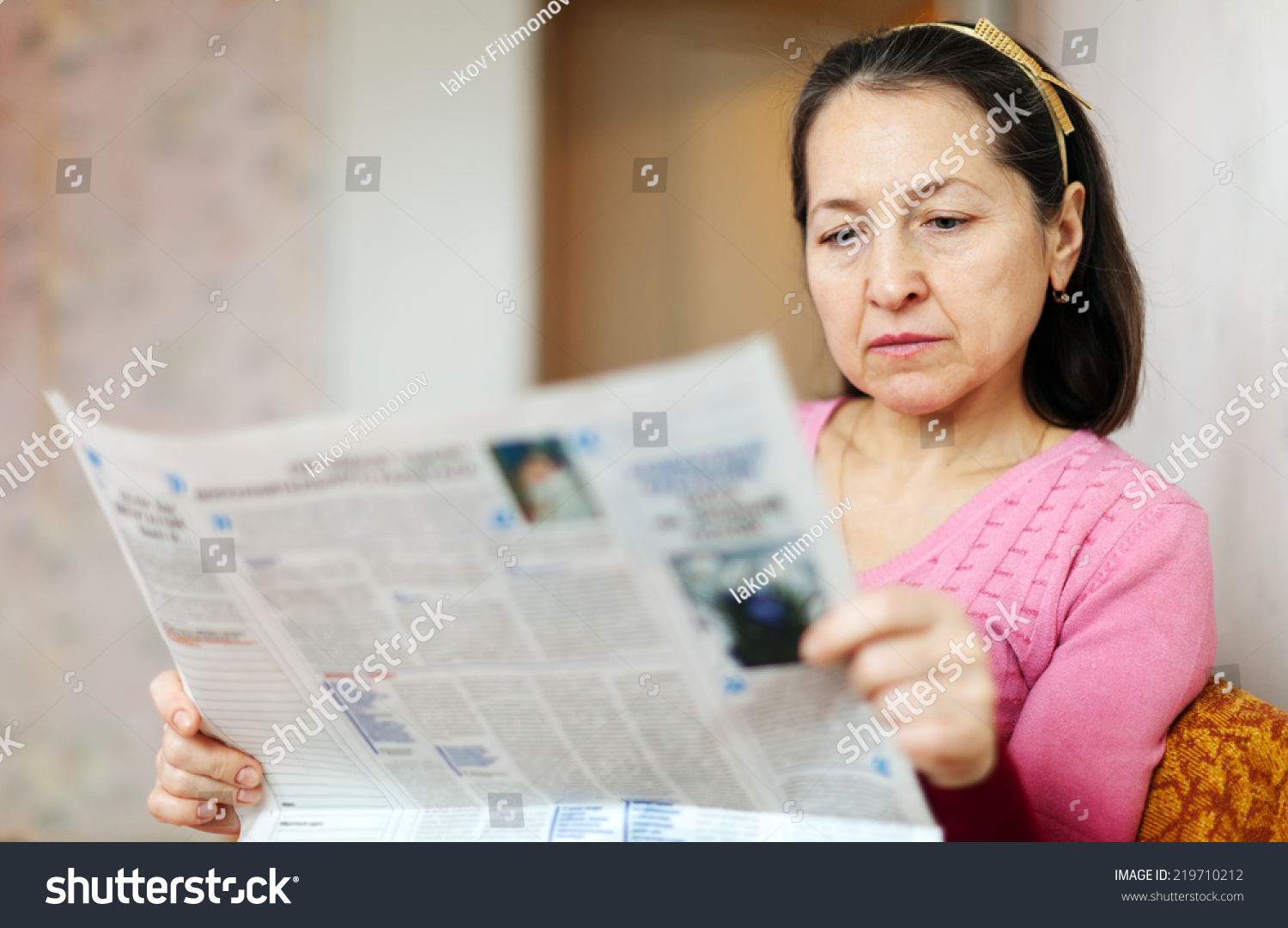 Serious Mature Woman Reading Newspaper On Stock Photo