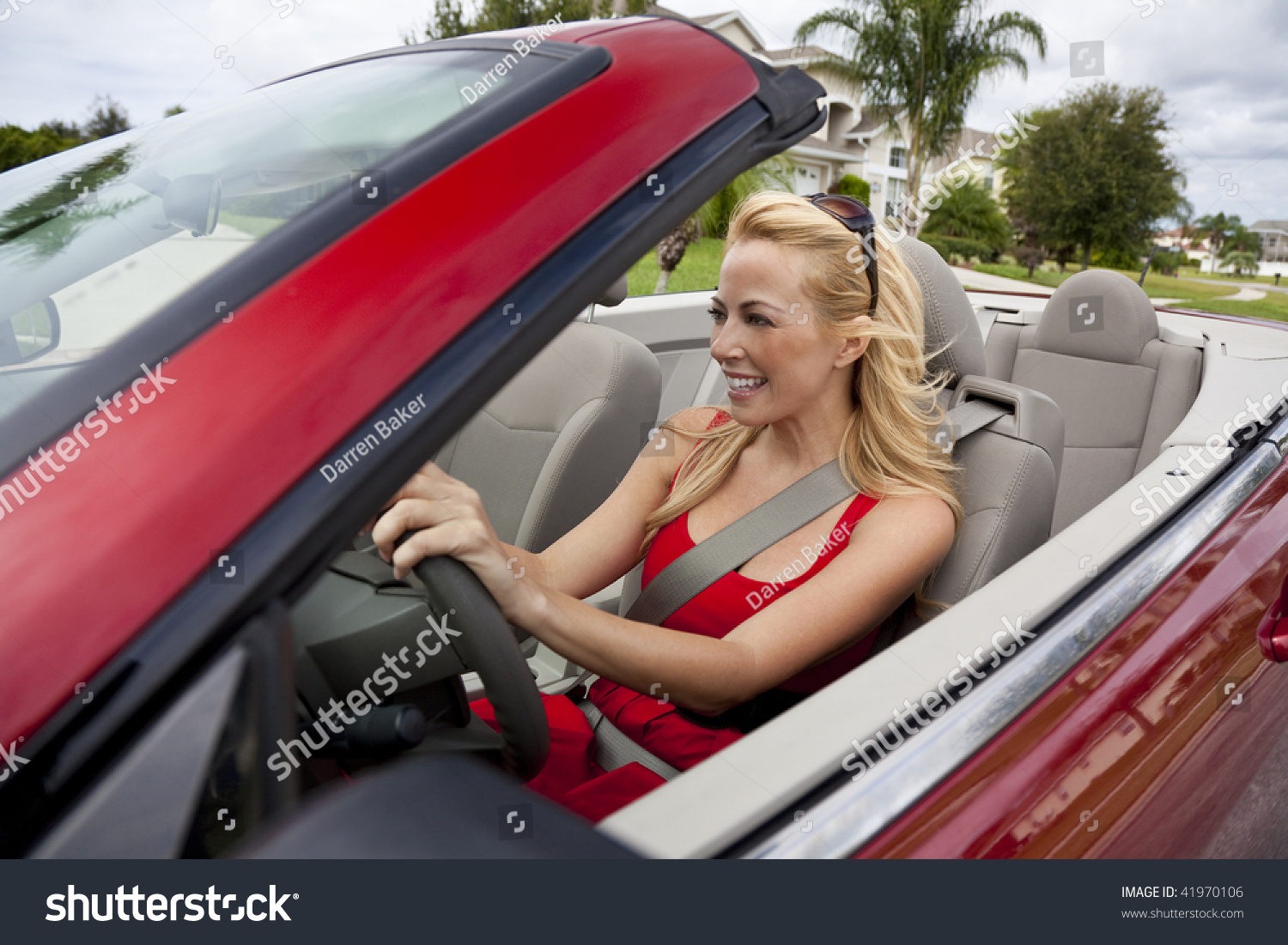 A Beautiful Young Blond Woman Driving Her Convertible Car Wearing A Red Dress And Sunglasses 6761