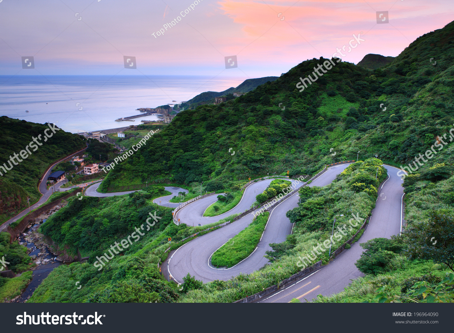 A Curvy Road Through The Grassy Hills With A View Of The Ocean. Stock 