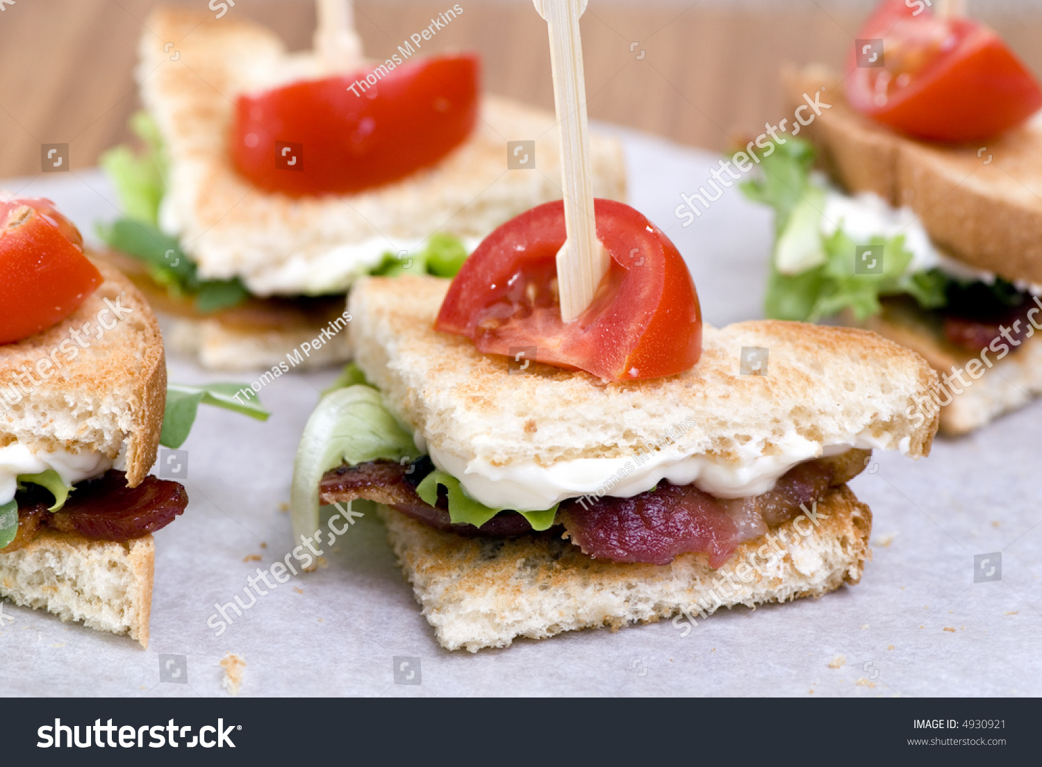 A Gourmet Blt Sandwich Cut Into Wedges With A Small Tomato On Top