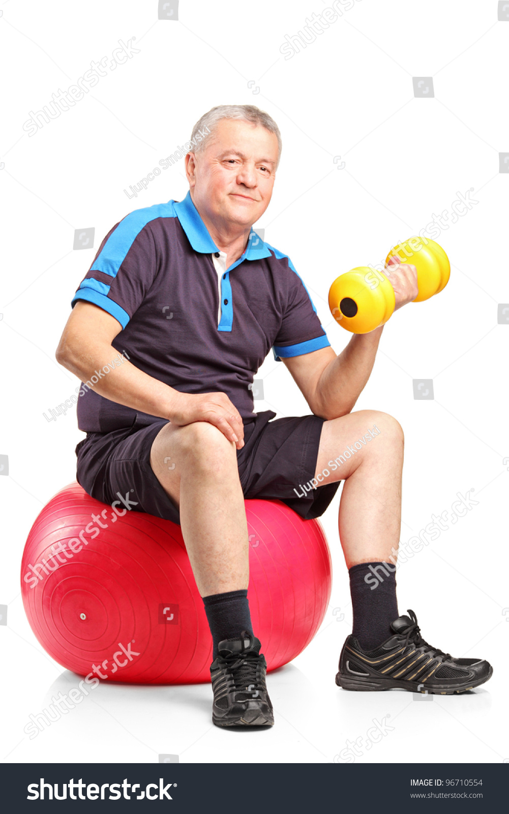 A Mature Man Lifting Up A Dumbbell Seated On A Fitness Ball Isolated On