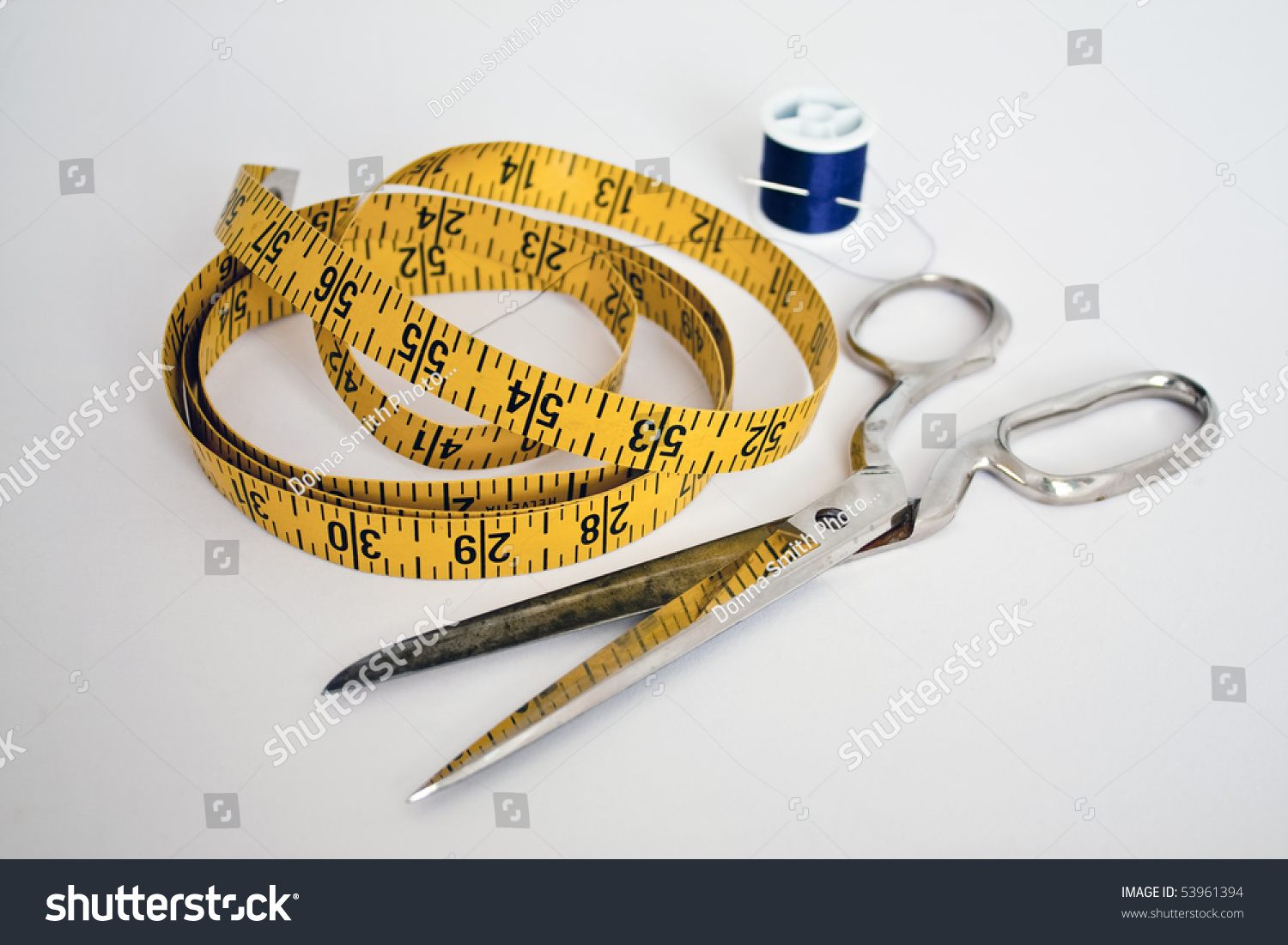 A Tailor's Tools: Scissors, Needle And Thread, And A Yellow Measuring 