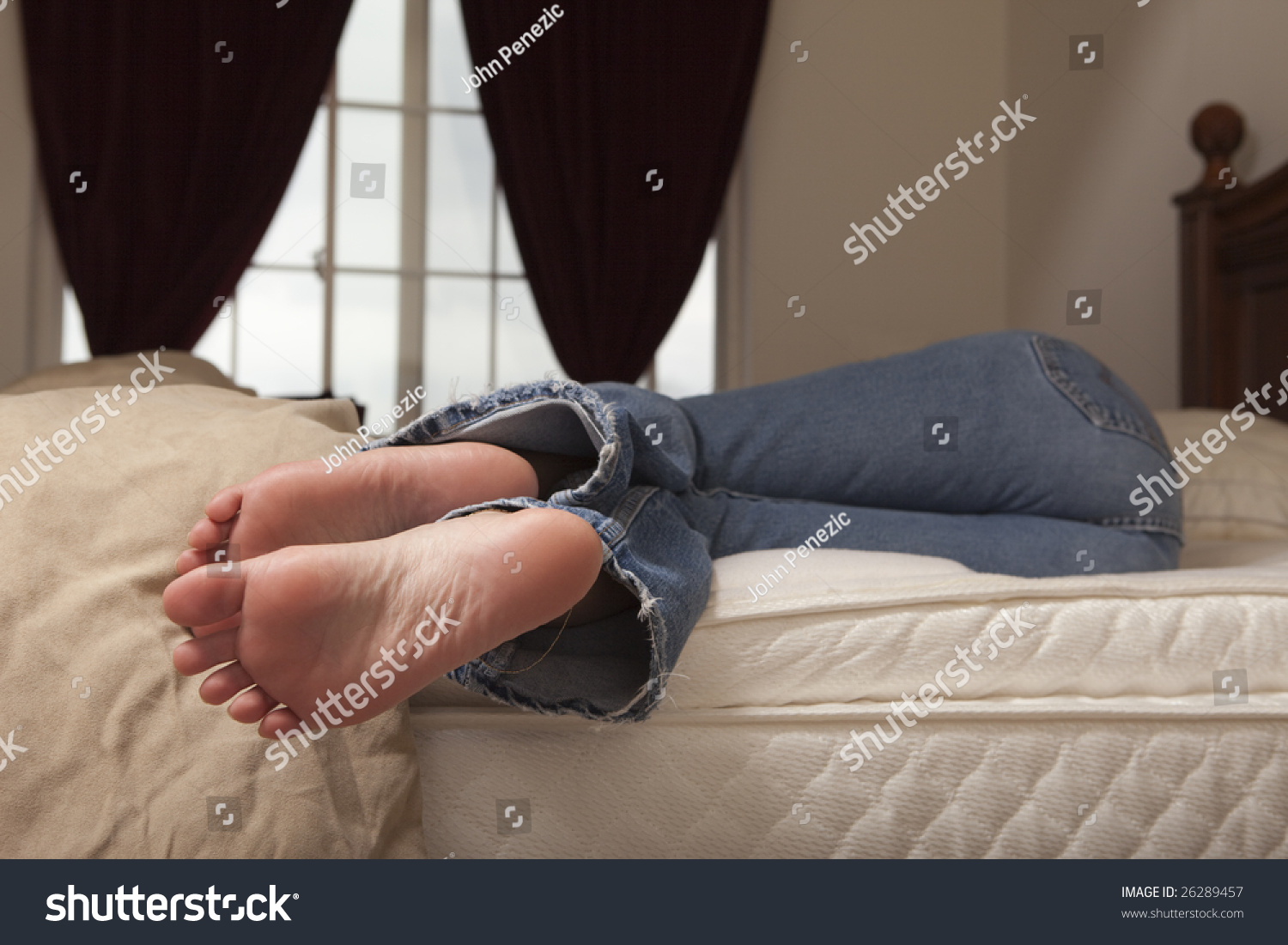 A Woman In Blue Jeans Relaxing On The Bed During The Day With Feet