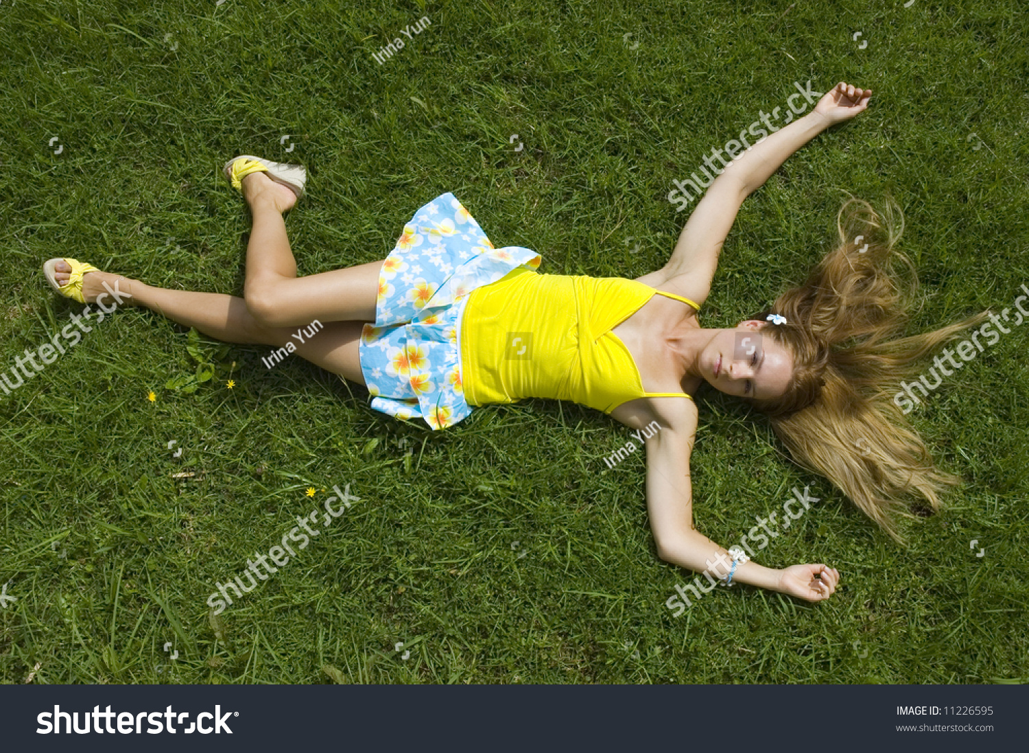 Young Woman Wearing A Mini Skirt Laying On Grass With Arms And Legs