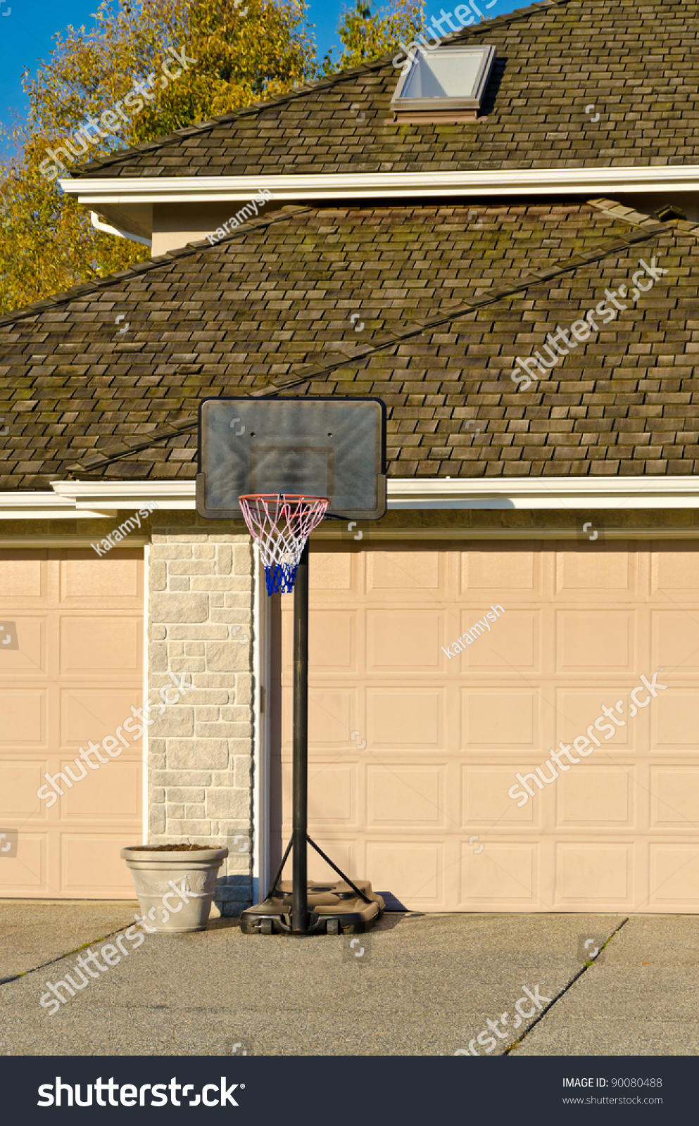 Basketball Hoop In Front Of Triple Garage Doors On Empty Suburban Residential Home Driveway