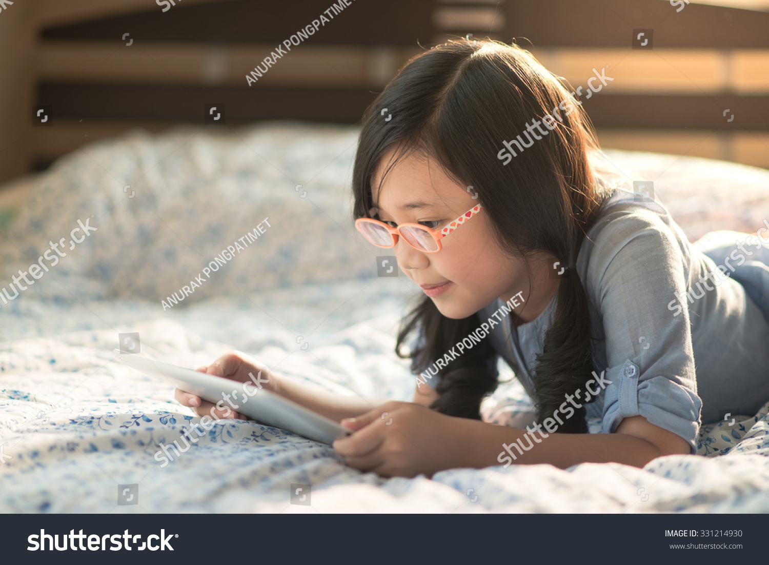 Beautiful asian girl using tablet while lying on bed Beautiful asian girl using tablet while lying on bed