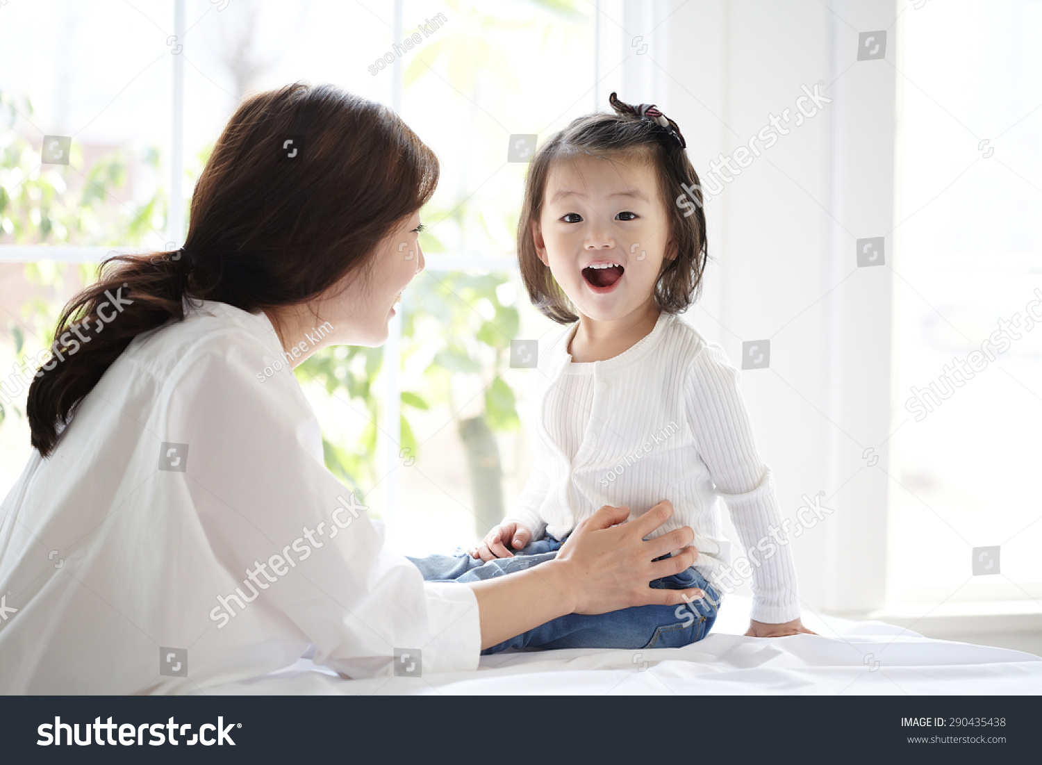 Beautiful Asian Mom And Her Cute Daughter Kissing With Love While Looking At Each Other Stock