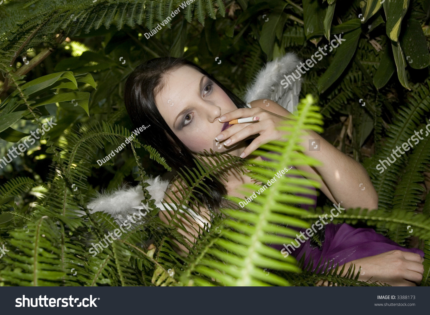 Beautiful Brunette Evil Fairy Busy Smoking A Cigarette In Between Plants Stock Photo